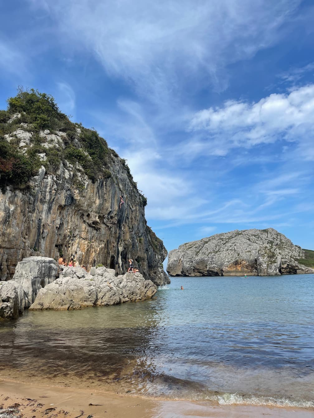Playa de Cuevas del Mar en Llanes, Asturias, con sus característicos afloramientos de roca caliza y aguas turquesas, ideal para escalada deportiva y baño.