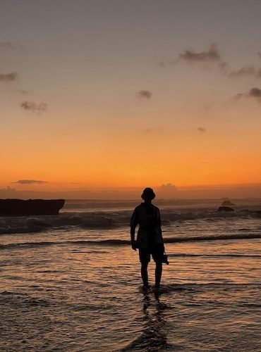 Atardecer dorado en Bali - Silueta de Daniel contemplando el sol, con cielo en tonos rojos y naranjas